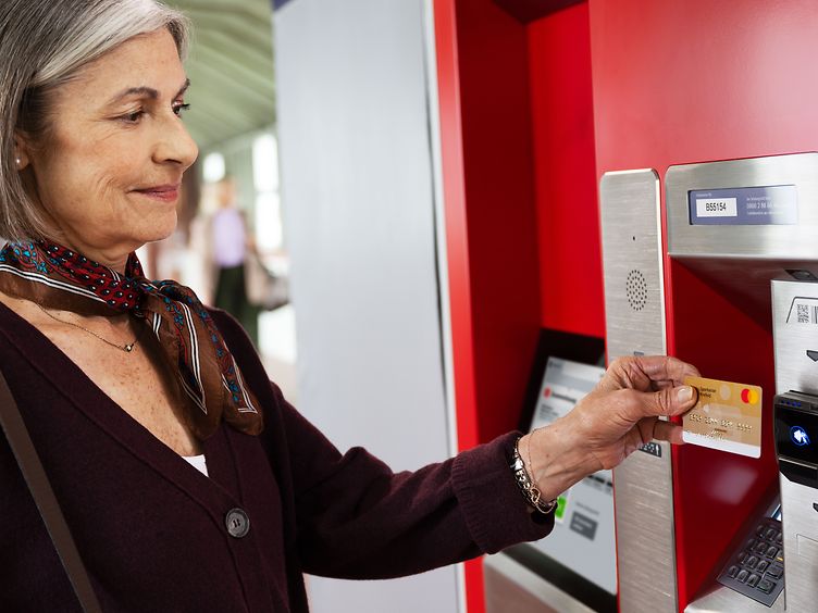 Frau bezahlt am Fahrkartenautomat mit EC-Karte