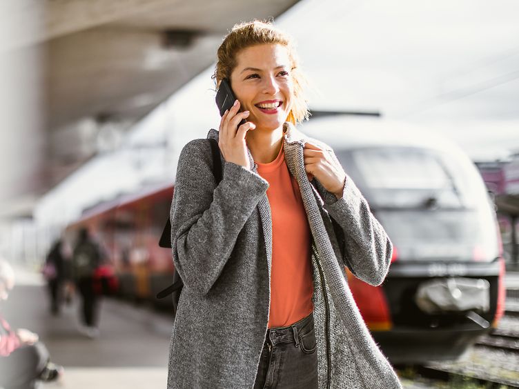 Frau telefoniert am Bahnhof