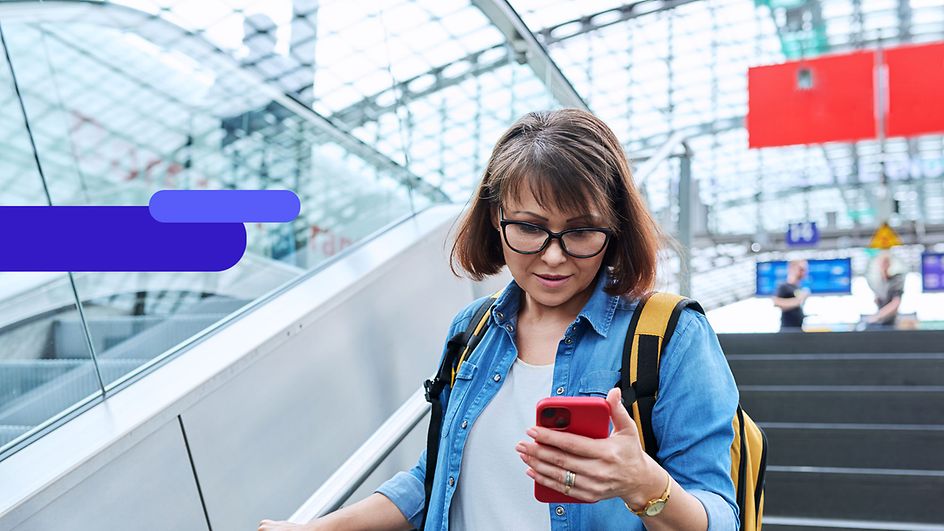 Frau mit Smartphone am Bahnhof